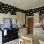 Wallpaper with a bright pattern on a dark background has become an excellent background for a light kitchen set