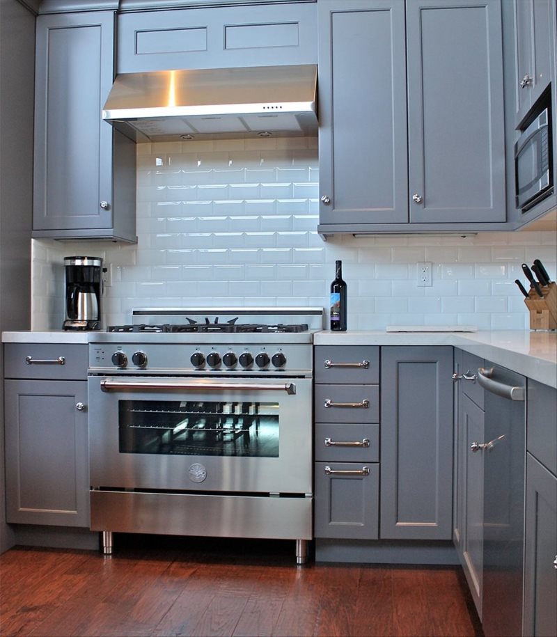 Gray stove with hanging hood in the corner kitchen