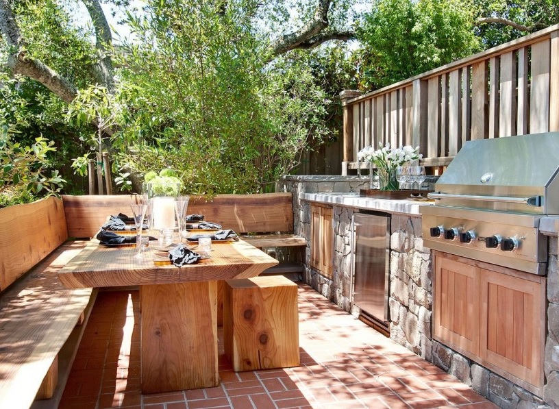 Open summer kitchen under the crowns of tall trees