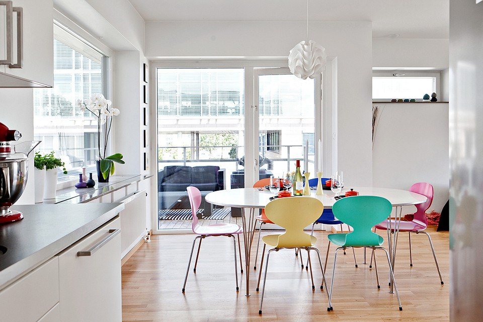 Chaises de différentes couleurs dans la cuisine avec des murs blancs