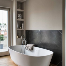 White acrylic bathtub in room with wooden floor