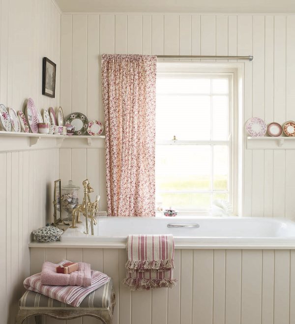 Un rideau coloré sur la fenêtre de la salle de bain dans le style du shabby chic