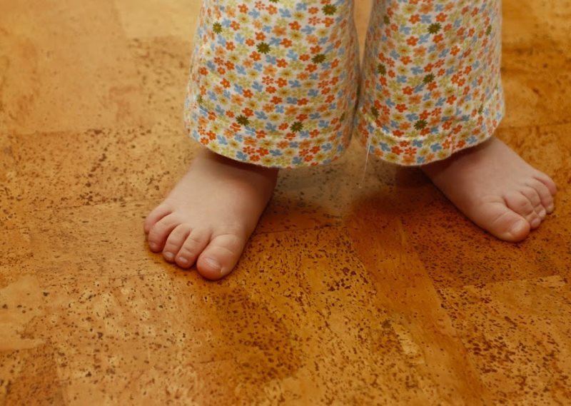 Piccolo bambino sul pavimento di sughero nel bagno