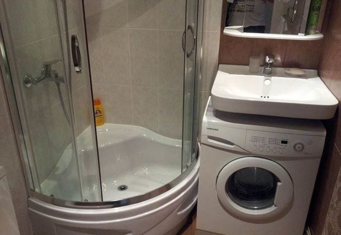 Corner cabin in a small bathroom with a washing machine