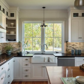 Évier sous la fenêtre de la cuisine dans une maison de campagne