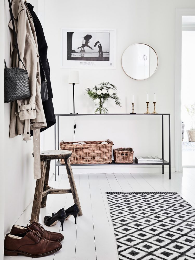 Three-legged wooden stool in a white hallway