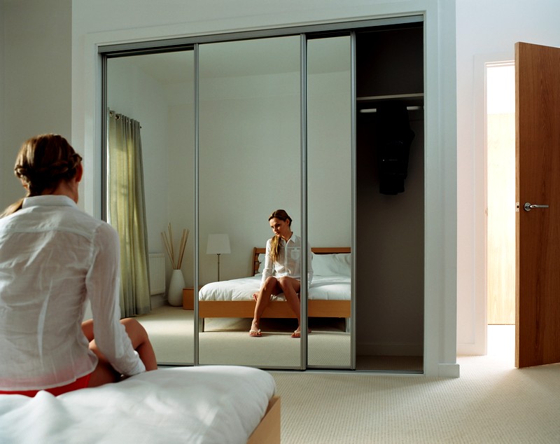 Reflet d'une jeune fille dans une armoire à miroir dans une chambre