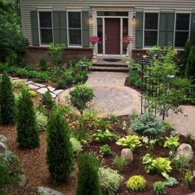 Parterre de fleurs avec des plantes tolérantes à l'ombre devant l'entrée de la maison