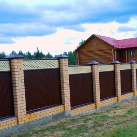 Fence with brick pillars on the slope of the plot