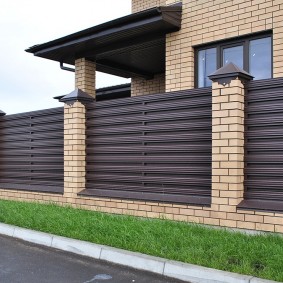 A narrow strip of green grass along the fence of a private house