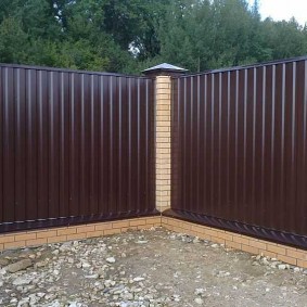 Corner of a summer cottage with a fence of dark brown color