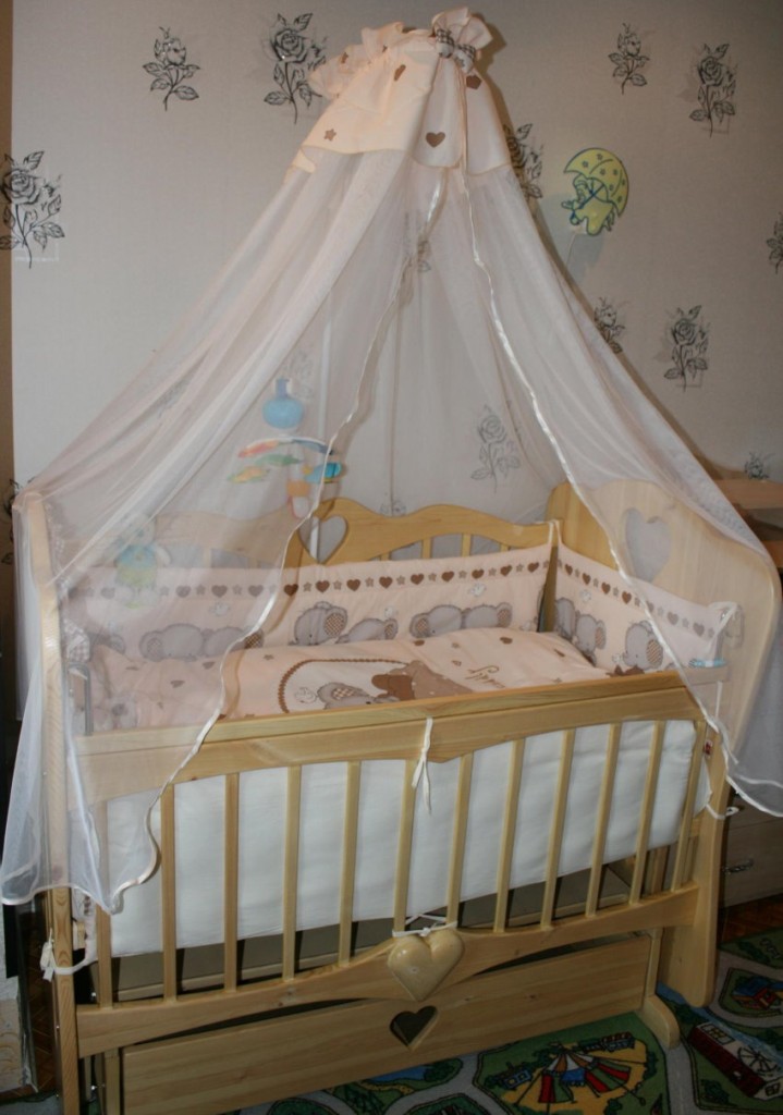 Auvent avec trépied réglable sur un lit de bébé en bois