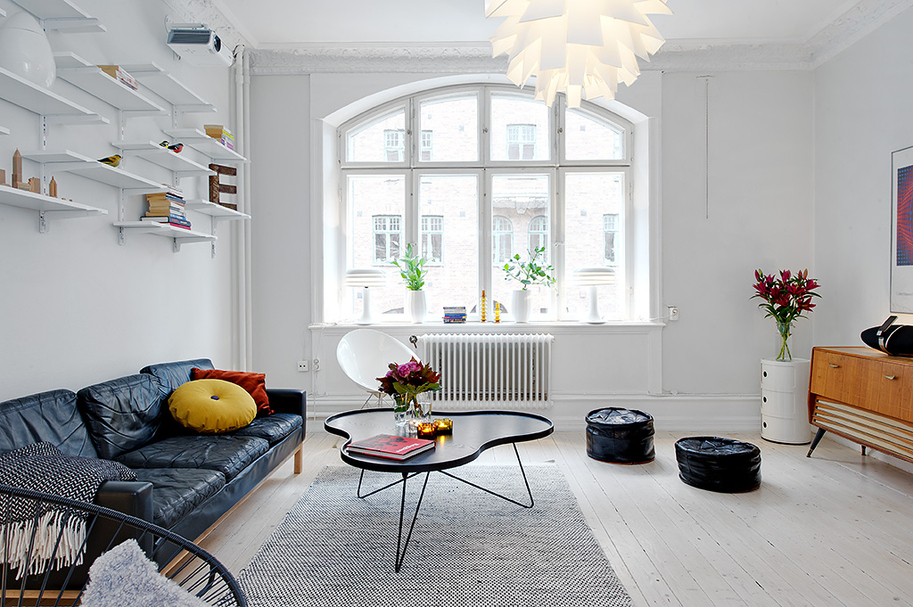 Canapé noir dans un appartement aux murs blancs