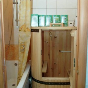 Mini-sauna en forme de tonneau en bois près du bain