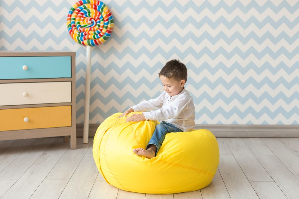 Tout-petit sur une chaise pouf jaune dans sa chambre