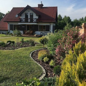 Mixborder with conifers near a brick fence